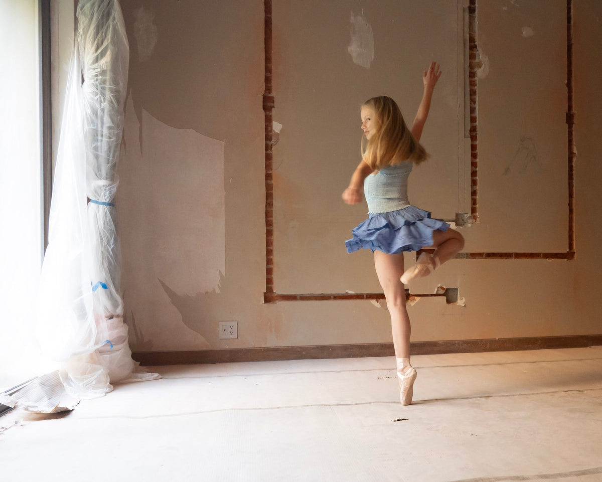 Vuelta sobre la punta del pie con falda corta de olanes azul y brazo extendido — campaña Bailarinas, Amor Amore