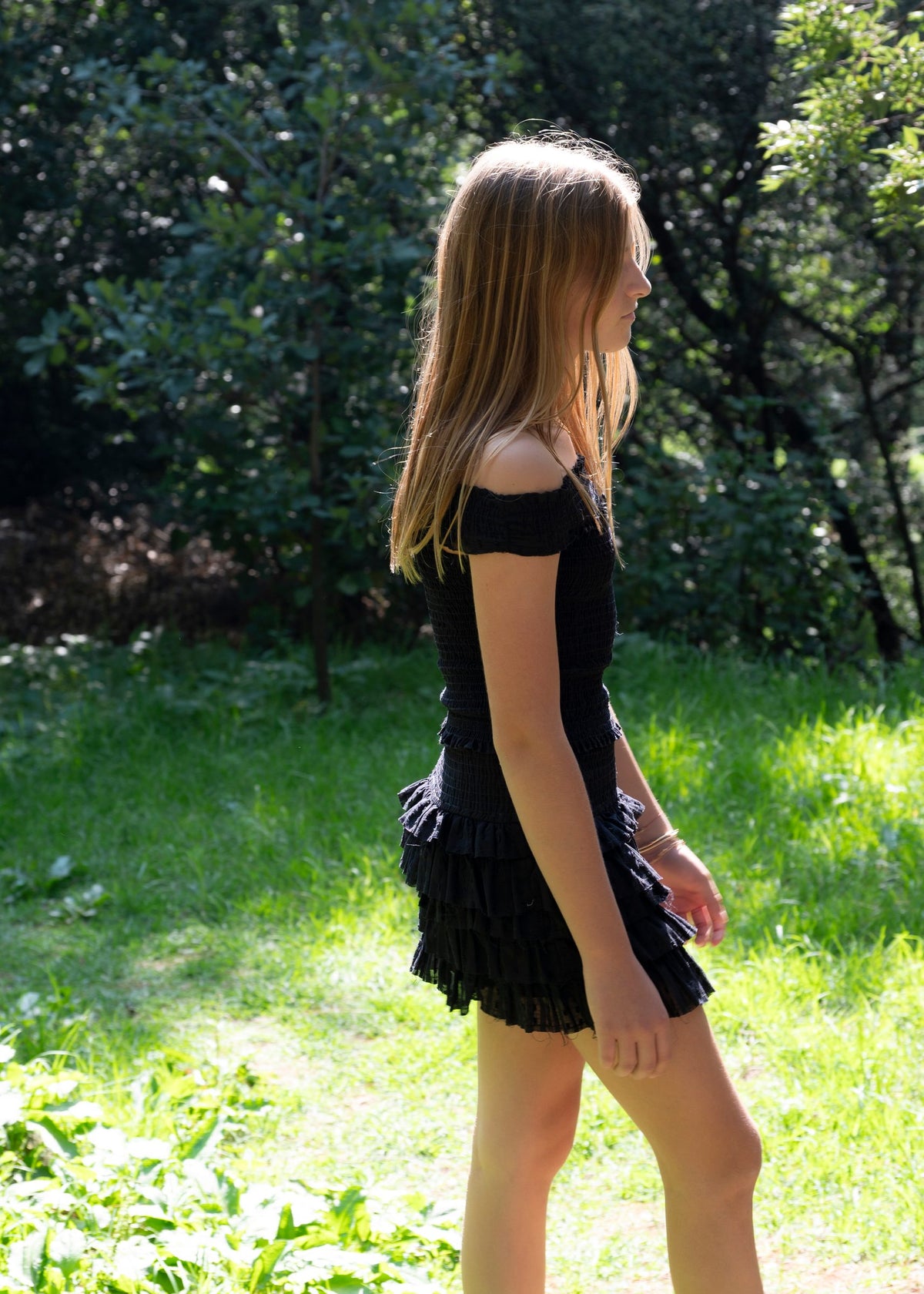 Conjunto negro de top de hombros descubiertos y falda corta de olanes entre los árboles — campaña Bosque, Amor Amore