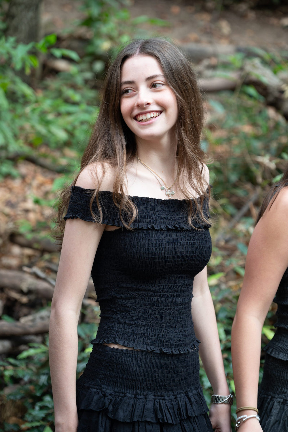 Conjunto negro de cuerpo fruncido y falda corta de olanes entre la vegetación del bosque — campaña Bosque, Amor Amore