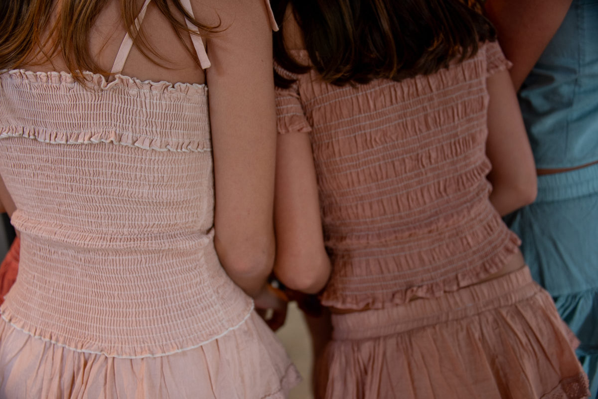 Detalle de dos tops rosa palo de cuerpo fruncido vistos de espaldas — campaña Collabs, Amor Amore