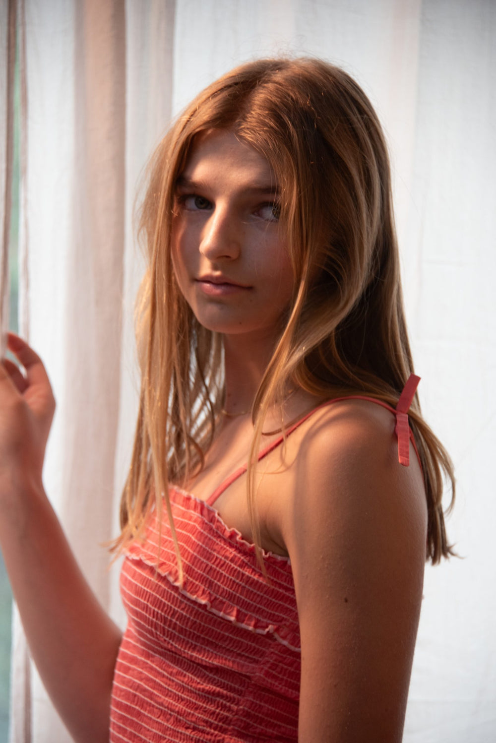 Top naranja de tirantes anudados y cuerpo fruncido, junto a la cortina blanca — campaña Collabs, Amor Amore