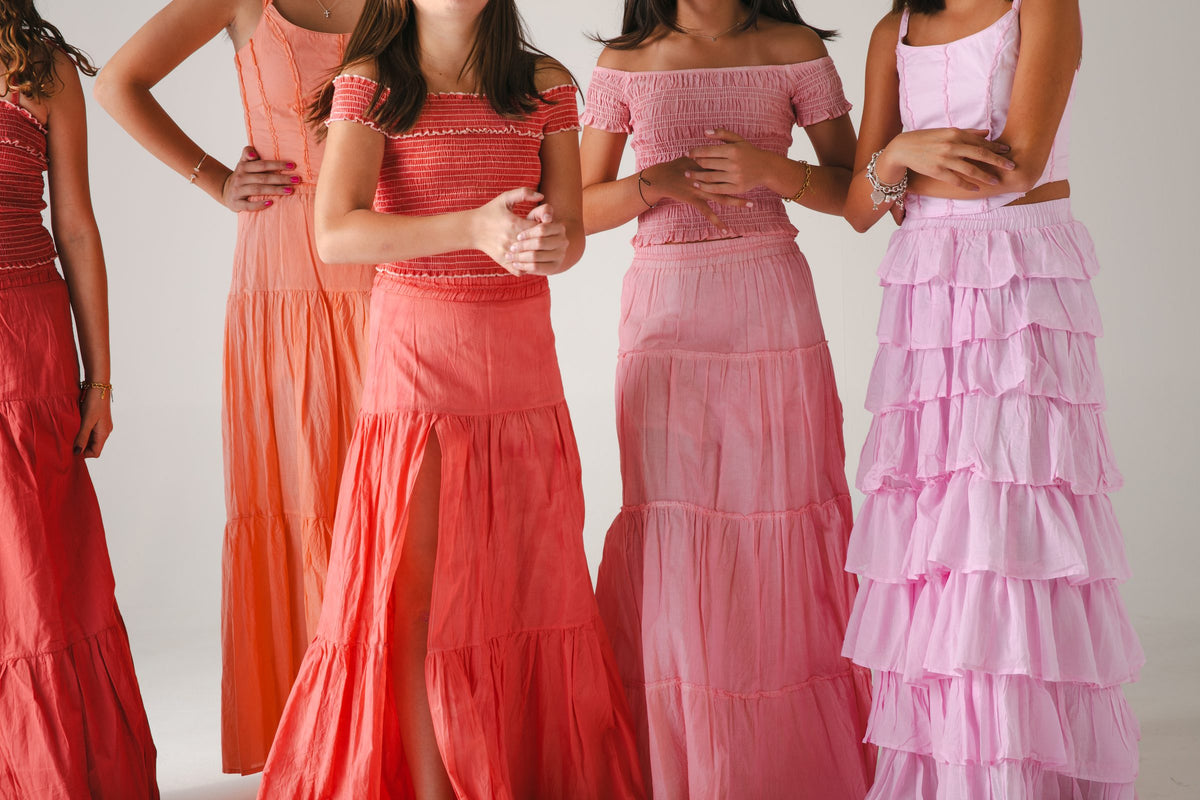 Cinco faldas largas en tonos rosa, naranja y vino, encuadre a la altura de la cintura — campaña Estudio, Amor Amore