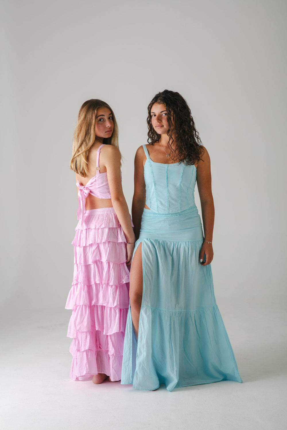 Conjunto rosa de olanes volteando a la cámara junto a falda larga turquesa con abertura — campaña Estudio, Amor Amore