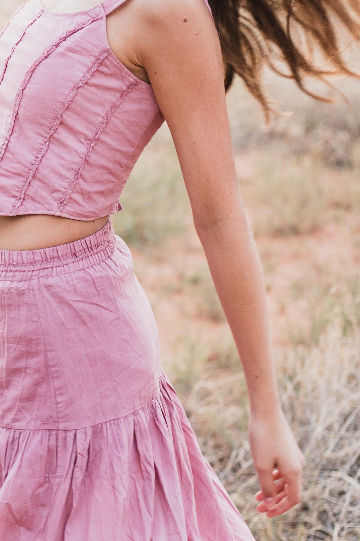 Detalle del top de tirantes y la falda larga escalonada rosa palo, de perfil — campaña Montaña, Amor Amore