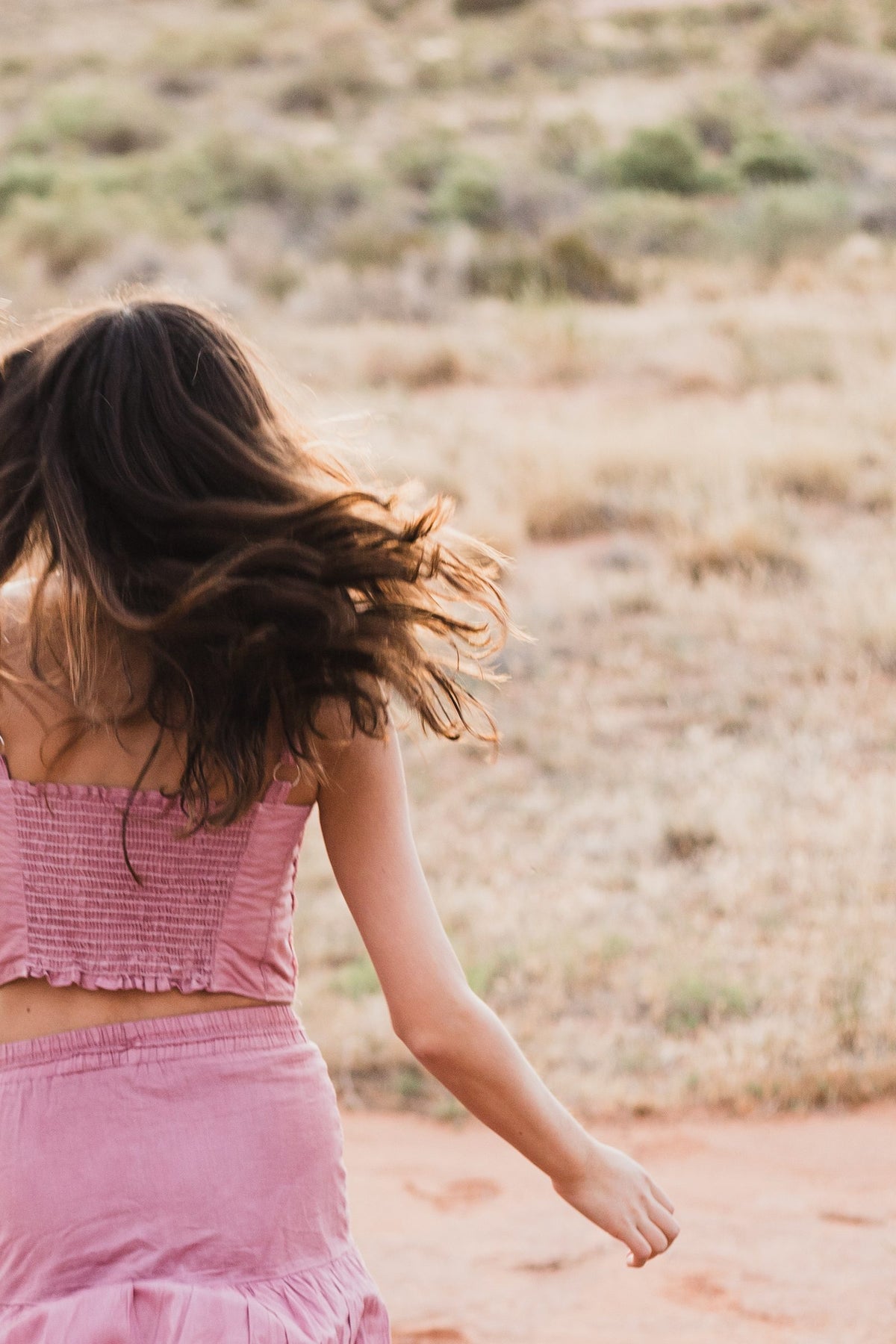 Top de hombros descubiertos rosa palo visto de espaldas, con el cabello al viento — campaña Montaña, Amor Amore