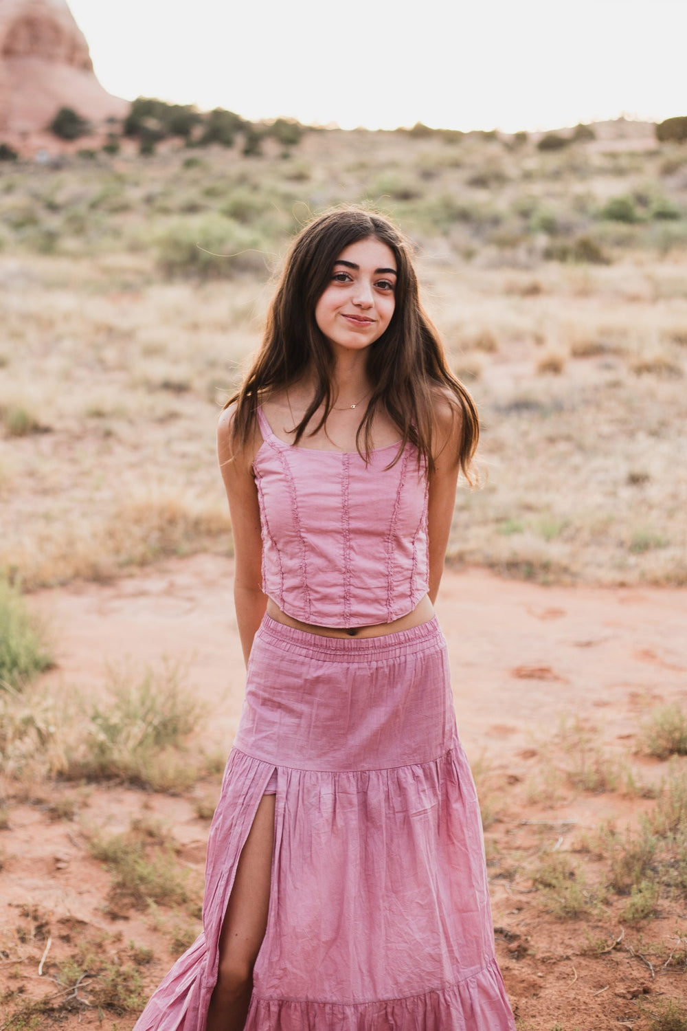Conjunto rosa palo de pie frente a la cámara, con formaciones rocosas al fondo — campaña Montaña, Amor Amore