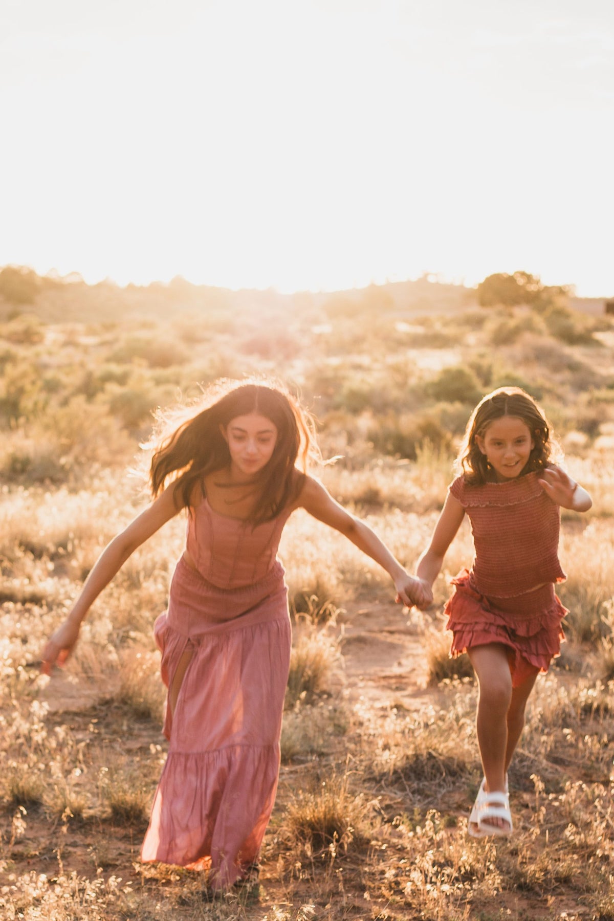 Dos conjuntos corriendo de la mano hacia la cámara entre los pastos secos — campaña Montaña, Amor Amore