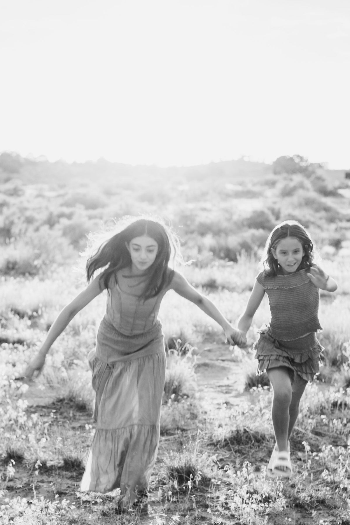 Blanco y negro de dos conjuntos corriendo de la mano por el campo abierto — campaña Montaña, Amor Amore