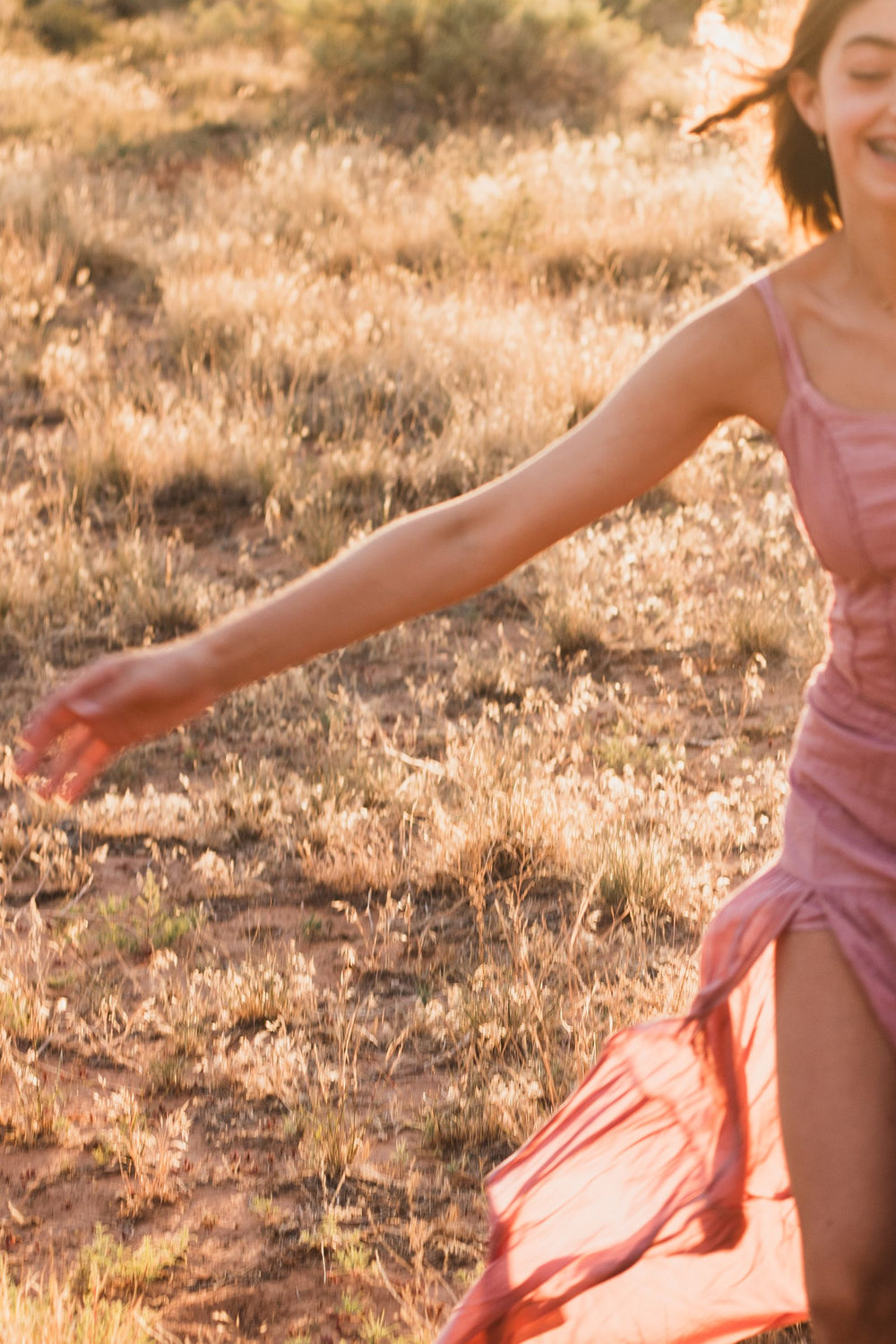 Falda rosa palo con abertura al vuelo y brazo extendido, con el sol de frente — campaña Montaña, Amor Amore