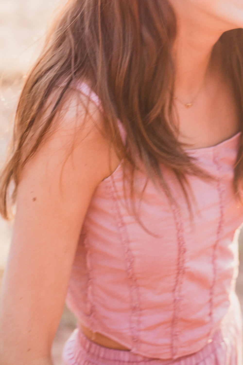 Detalle de las costuras verticales del top de tirantes rosa palo, con el cabello suelto — campaña Montaña, Amor Amore