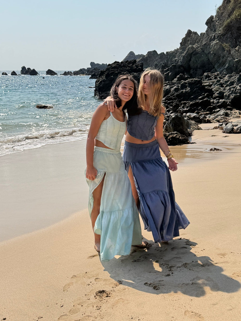 Dos conjuntos de falda larga abrazadas en la orilla — campaña Playa, Amor Amore