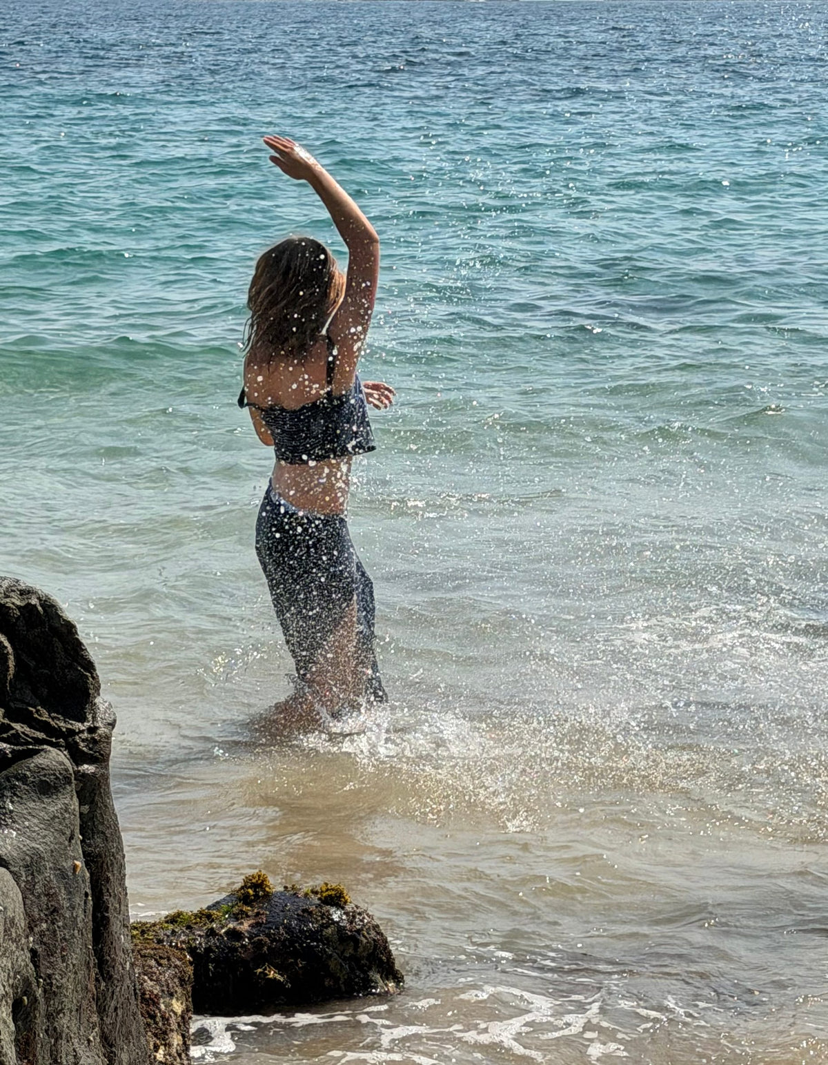Falda larga en el mar, salpicando agua con el brazo en alto — campaña Playa, Amor Amore